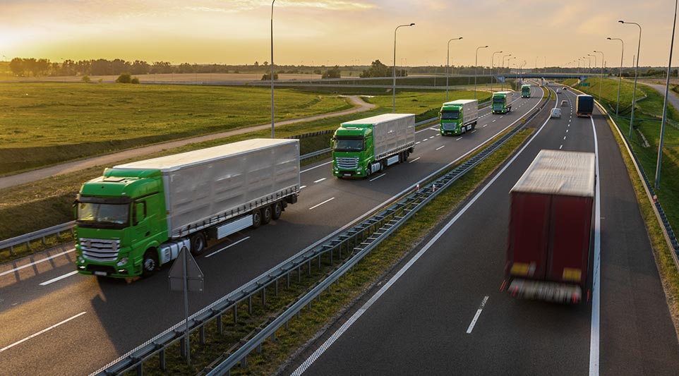 Zestawy ciężarowe w trasie na autostradzie o zachodzie słońca